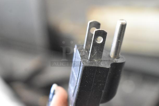 Close-up of a black 110V plug for a commercial countertop citrus juicer.