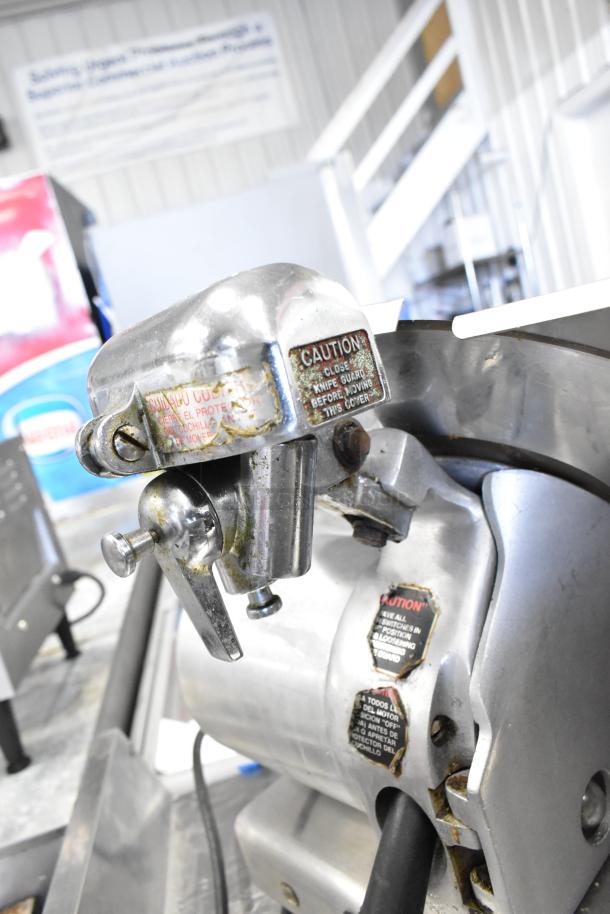 Globe commercial countertop meat slicer with blade sharpener, 115 volts, 1 phase. Features caution labels and metal finish.