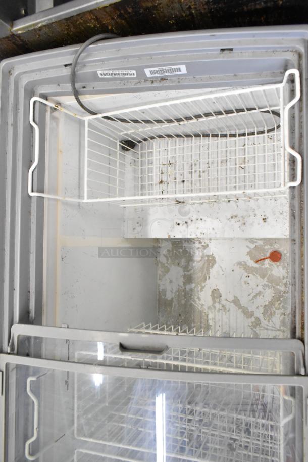 AHT RIO S 125 commercial freezer merchandiser, 115 volts, 1 phase, visible wear and stains inside, wire basket and label shown.