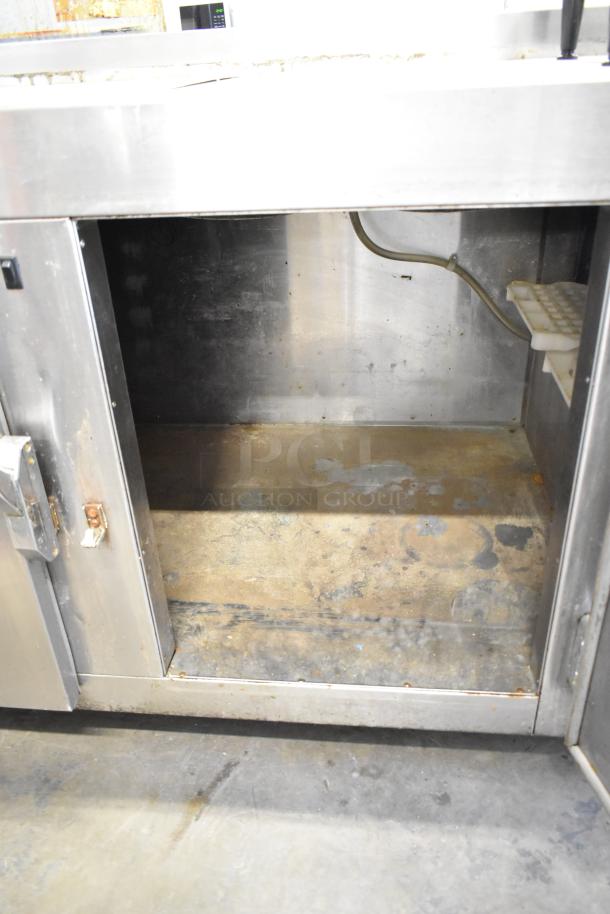 Commercial 3 Door Undercounter Cooler on casters, stainless steel, 115 volts, used condition, visible interior wear.