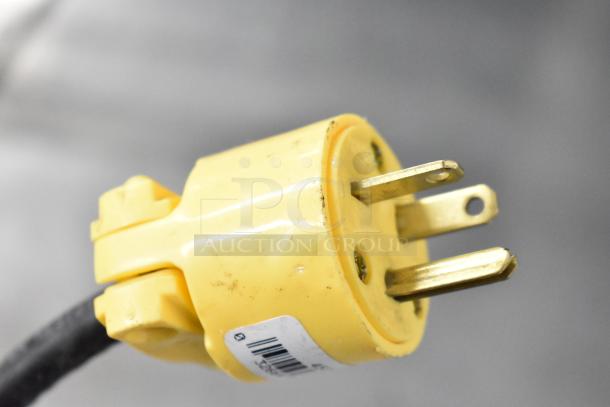 Yellow electrical plug of Lassele LT-1833R cooler. Features three prongs and attached barcode label.