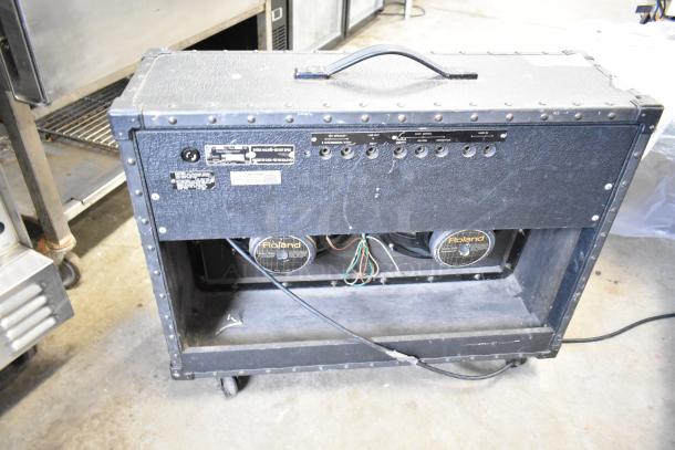 Roland Jazz Chorus 120 speaker on casters, visible rear panel with input/output jacks, two Roland speakers, used condition.