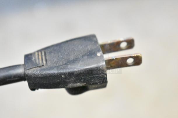 Close-up of a prong-style power plug, slightly worn, suggesting use.