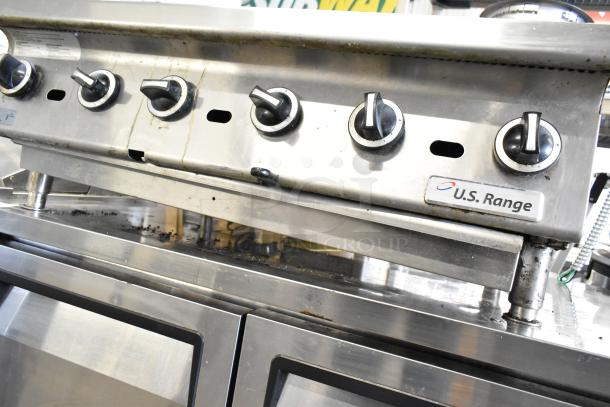 US Range commercial gas charbroiler with stainless steel knobs, showing signs of use. U.S. Range brand label visible.