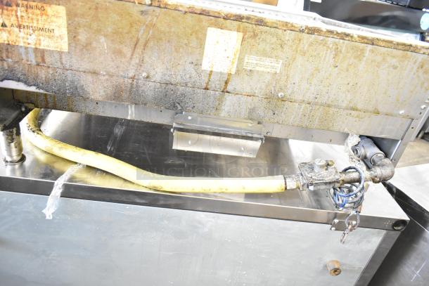 US Range Commercial Gas Charbroiler Grill, shows signs of use with visible wear and a connected gas hose.