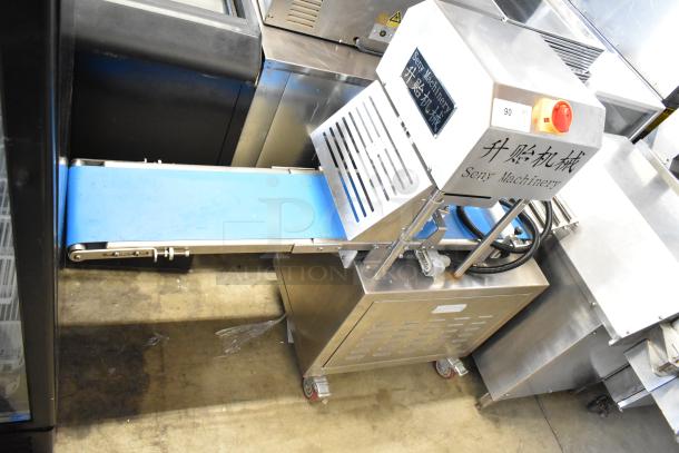 Seny Machinery commercial slicer and conveyor machine on casters, 220 volts, stainless steel finish, logo visible.