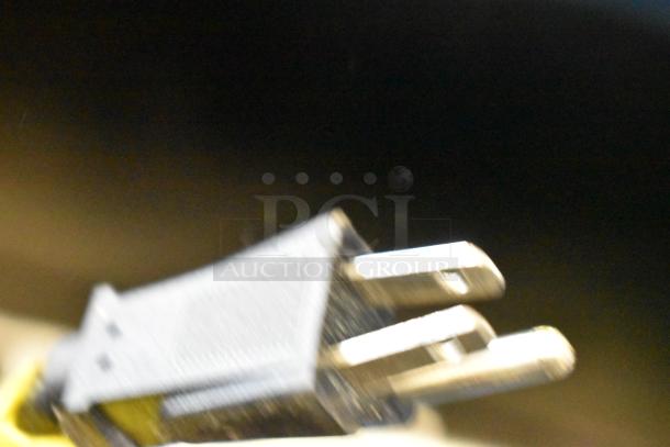 Blurry close-up image of a power plug, potentially for the 2021 IDW G-12SI-N-3-3-4-B-5 single door cooler.