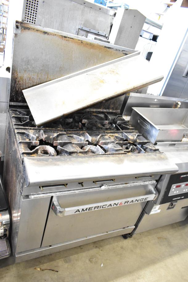 American Range commercial 6 burner gas range with oven, over shelf, and back splash. Appears used with visible wear.