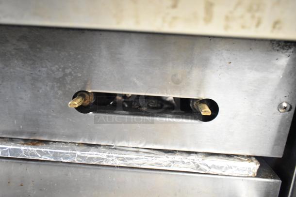 Metal control panel of American Range commercial gas 6 burner range with visible adjustment knobs and surface wear.