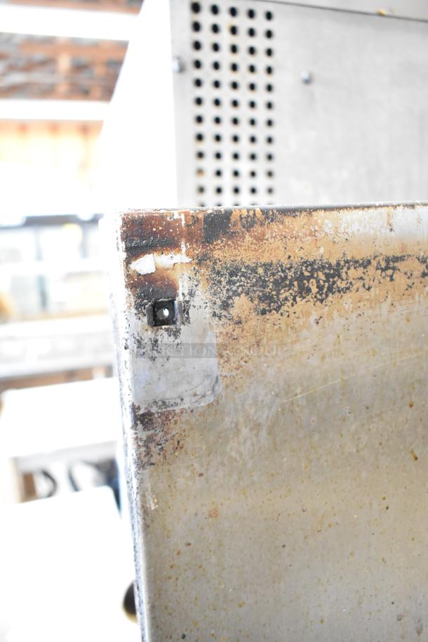 Close-up of rusted corner on American Range 6 burner commercial gas range. Visible wear and metal corrosion present.