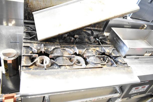 American Range commercial gas-powered 6 burner range with oven, over shelf, and back splash, showing wear and use marks.