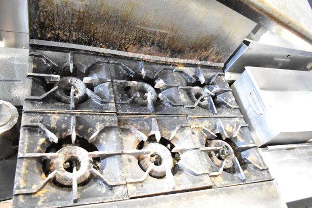 American Range commercial gas 6-burner range with oven, over shelf, and backsplash. Used condition, visible wear.