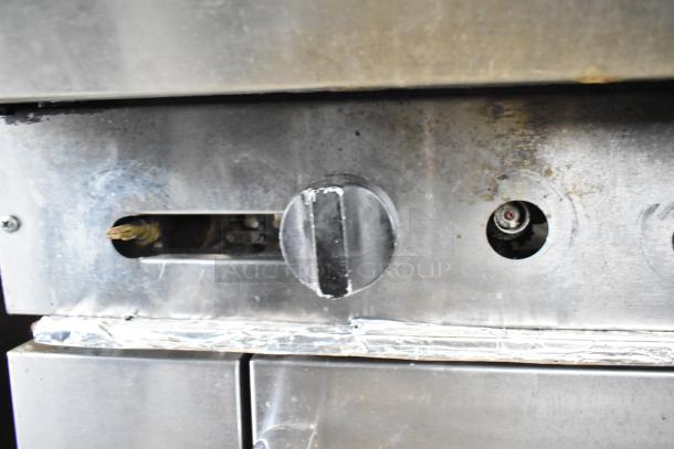 American Range commercial gas-powered 6-burner range with oven, featuring control knobs and stainless steel finish. Some wear visible.