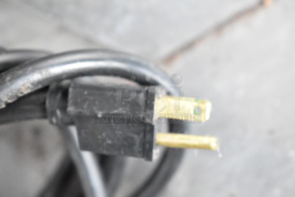 Close-up of a black electrical power plug with brass prongs, part of the Garland MCO-GS-10S convection oven setup.