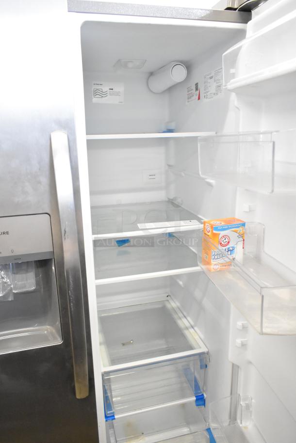 Brand new Frigidaire FRSS2623ASN cooler/freezer with ice/water dispenser. 115V, 1 Phase. Interior shelves visible.