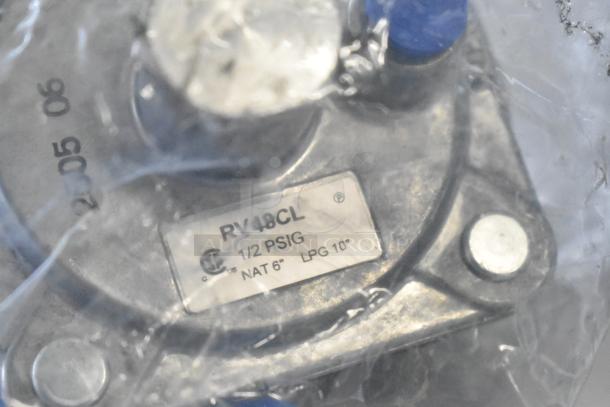Label on a metal component stating "RV48CL, 1/2 PSIG, NAT 6”, LPG 10”". Component is sealed in plastic packaging.