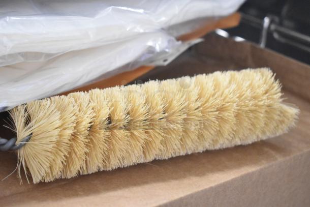 Commercial fryer cleaning brush with stiff bristles on a wire core, lying on a cardboard box.