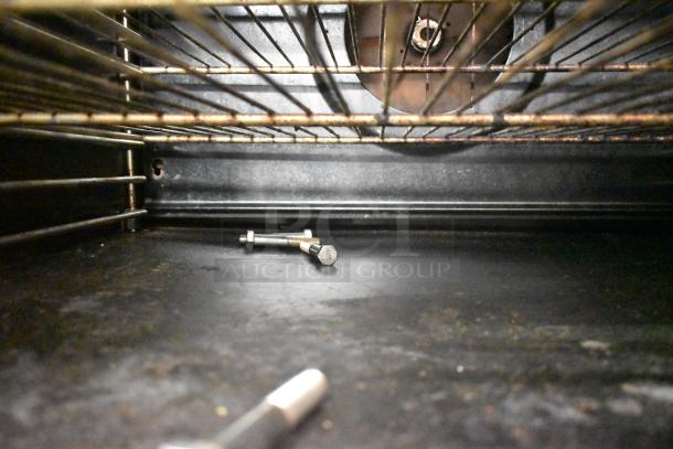 Blodgett commercial convection oven interior view, showing wire racks, some dust, and bolts on the floor. Oven in used condition.