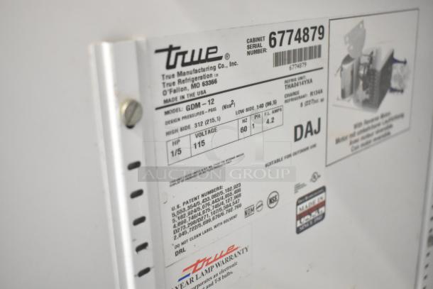 Metal tag on True GDM-12 cooler showing model details, 115 volts, 1 phase, serial number 6774879, made in USA.
