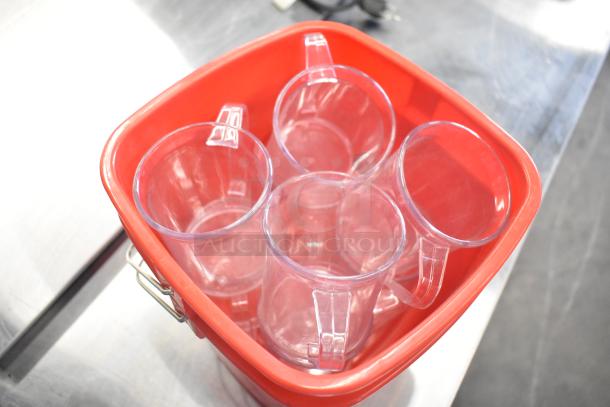 Red poly bucket containing clear poly pitchers, all in good condition. Auction offers 10 times the items for your bid.