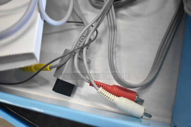 Wii console cables in box. Includes RCA connectors, emphasizing console's original packaging and condition.