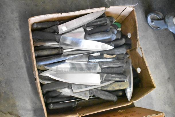 Cardboard box containing 230 sharpened stainless steel knives, featuring chef knives. Black handles, mixed conditions.