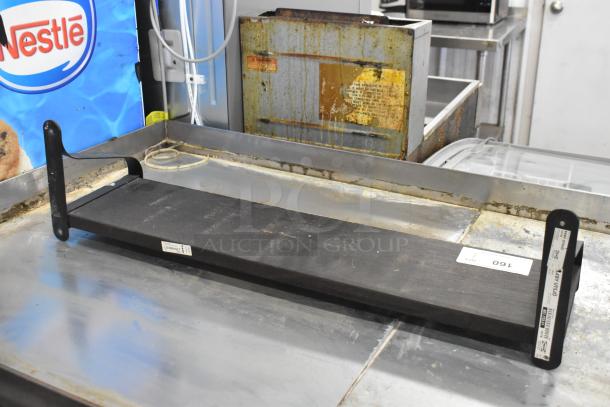 Black wall mount shelf with bracket supports and visible labels. Appears lightly used, suitable for storage or display.