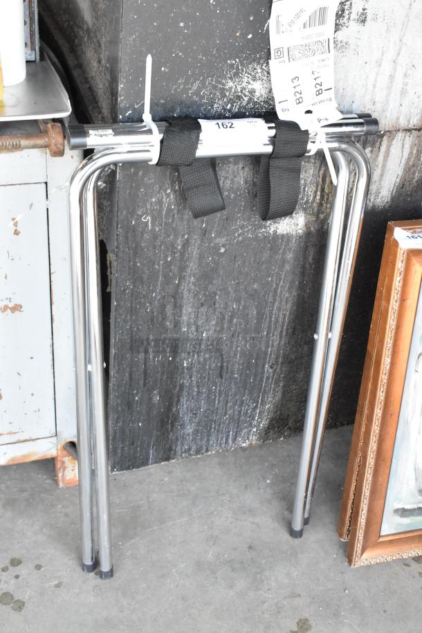 Chrome finish serving tray stand with foldable legs, black straps, and visible barcode tags. Used condition.