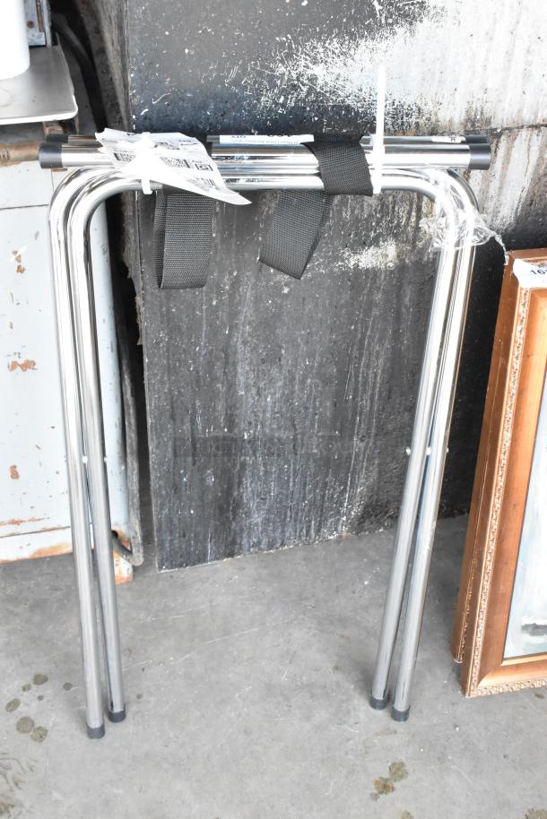 Chrome finish serving tray stand with foldable legs, black straps, and protective plastic wrap. Ideal for catering events.