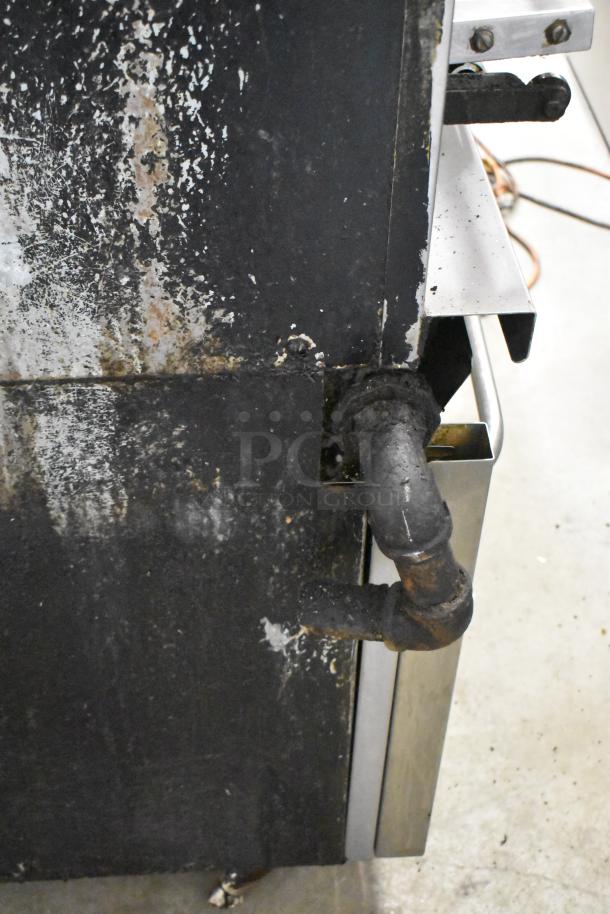 Montague Vectaire gas upright vertical broiler, showing side view with visible wear and utility pipe connection.