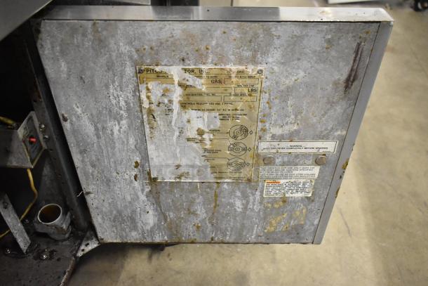 Pitco Frialator commercial gas deep fat fryer with visible wear and tarnished metal surfaces. Instruction and warning labels on front.