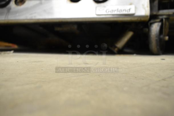 Garland Commercial Countertop Gas Griddle, ribbed surface, metal finish, on wheels. Features Garland logo, used condition.