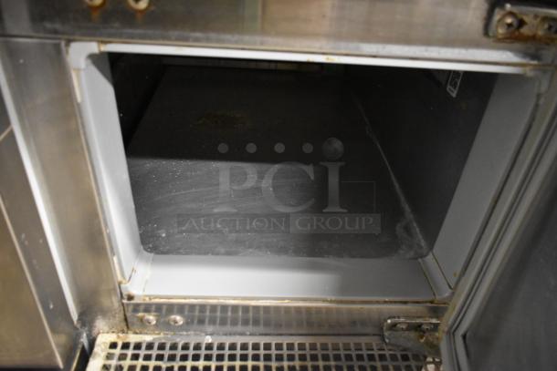 Continental CPA60 commercial pizza prep table interior, showcasing storage condition. Features two drawers, two doors, on casters.