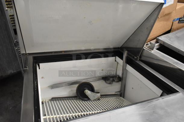 True TSSU-27-12M-B commercial sandwich salad prep table, open lid, seen on durable commercial casters.