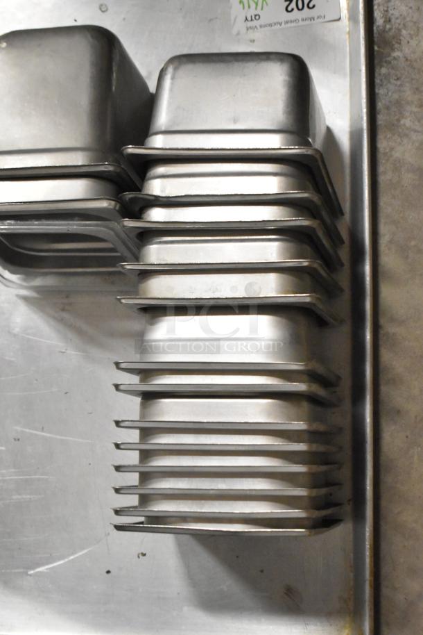 Stacked stainless steel drop-in bins and metal baking pan, 16 items, used condition, ideal for kitchen or catering use.