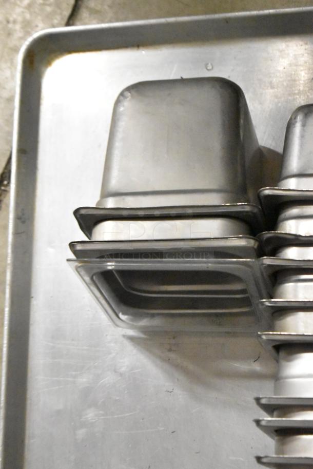 Stainless steel drop-in bins and metal baking pan, slightly used, stacked in an auction lot of 16 items.