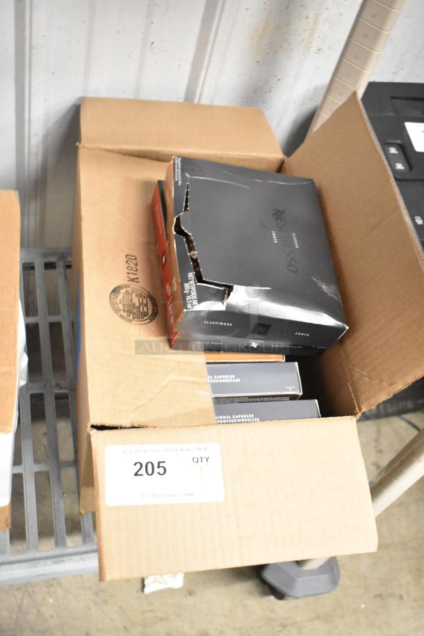 Box of Nespresso coffee/espresso grounds, damaged black packaging, labeled "Classiques" and "Forte," quantity 1, lot 205.