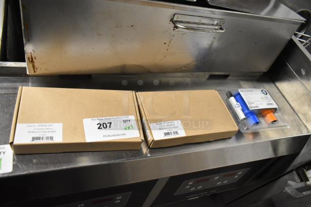 Three items including two HT03XL-BTI Li-Polymer Batteries in boxes and a Fargo DTC color ribbon in packaging, shown on a metal surface.