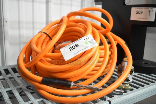 Coiled orange propane gas hose with metal fittings, auction tag shows item 208, quantity x2, on metal shelf.
