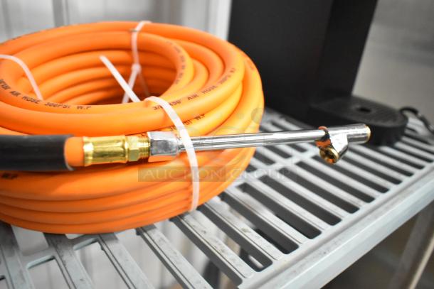 Orange propane gas hose coiled with brass connector, labeled "300 PSI W.P." on metal shelf, in new condition.