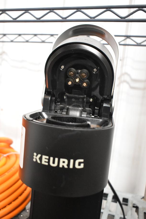 Keurig K900 single cup coffee machine, black, 120 volts, open top view. Visible label and Keurig branding.