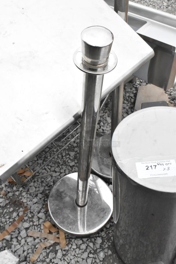 Three items including a metal trash can and two stainless steel stanchions, label reads "217 QTY x 3 PCIAuctions.com".