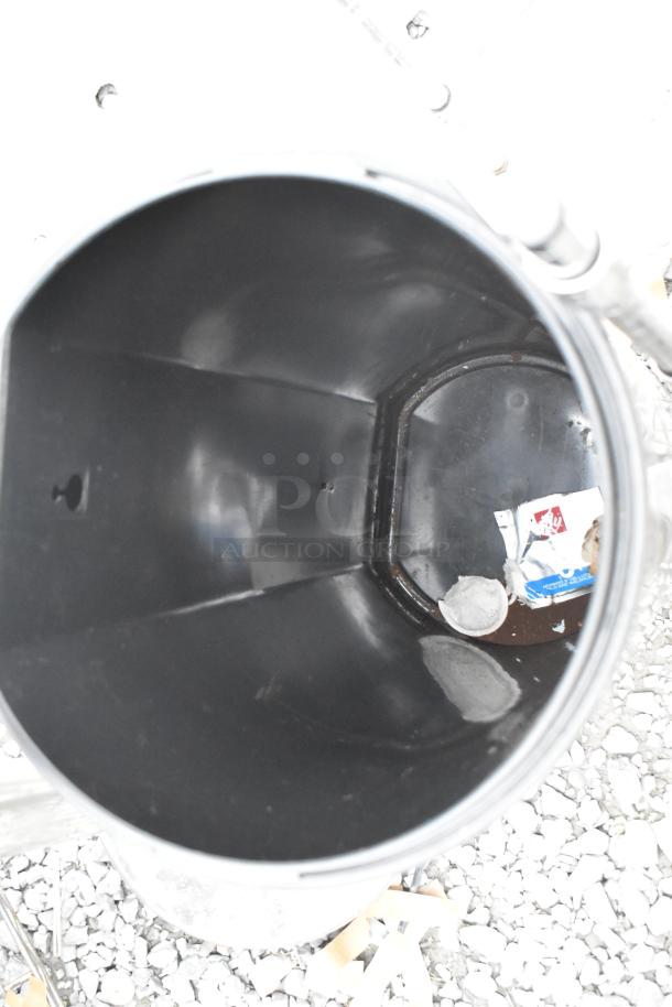 Black trash can interior; visible debris suggests used condition. Auction lot includes two stanchions.