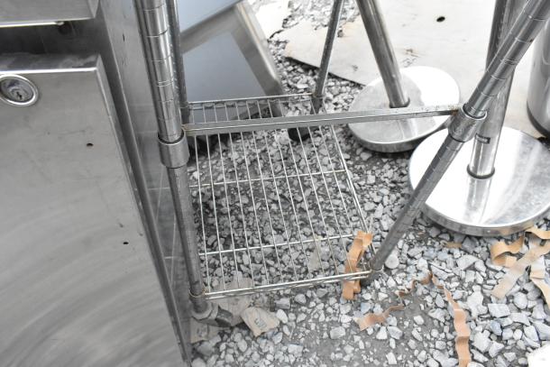 Stainless steel table with wire under shelf, durable construction, slight wear visible, ideal for commercial use.