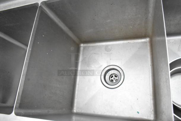 Commercial 3 bay stainless steel sink with faucet and handles, good condition, clean surface with visible drain.