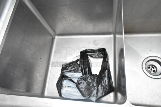 Commercial 3 bay stainless steel sink with faucet and handles, showing one compartment with a drain and plastic bag.