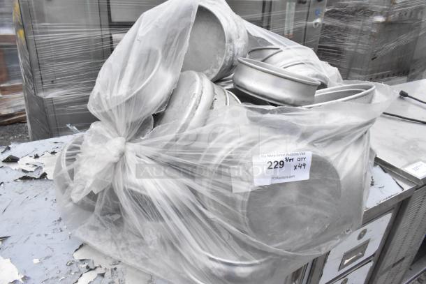 Bag of 49 round metal baking pans, bundled together. Clear plastic wrap with auction tag showing quantity and details.