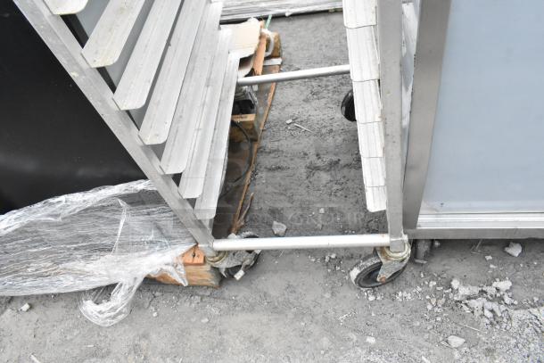Commercial pan transport rack with adjustable shelves on heavy-duty casters. Sturdy frame, moderate wear visible.