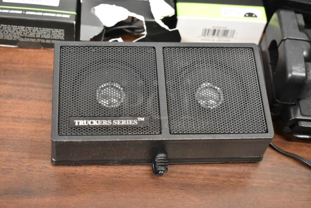 Truckers Series radio with dual speakers, visible label. Part of a lot including Uniden Pro505XL and various earbuds.