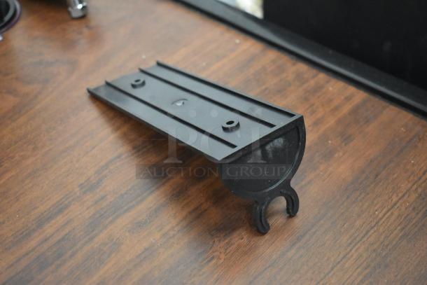 Black plastic radio mounting bracket on a wooden surface, designed for supporting devices securely.